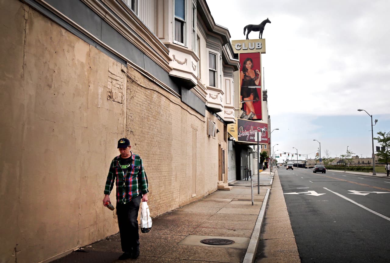 Un hombre camina en una calle que da a un club de striptease, uno de los pocos negocios que permanecen abiertos sobre la calle Martin Luther King. En septiembre de 2014 un cuarto de la población de la ciudad vivía en la pobreza.