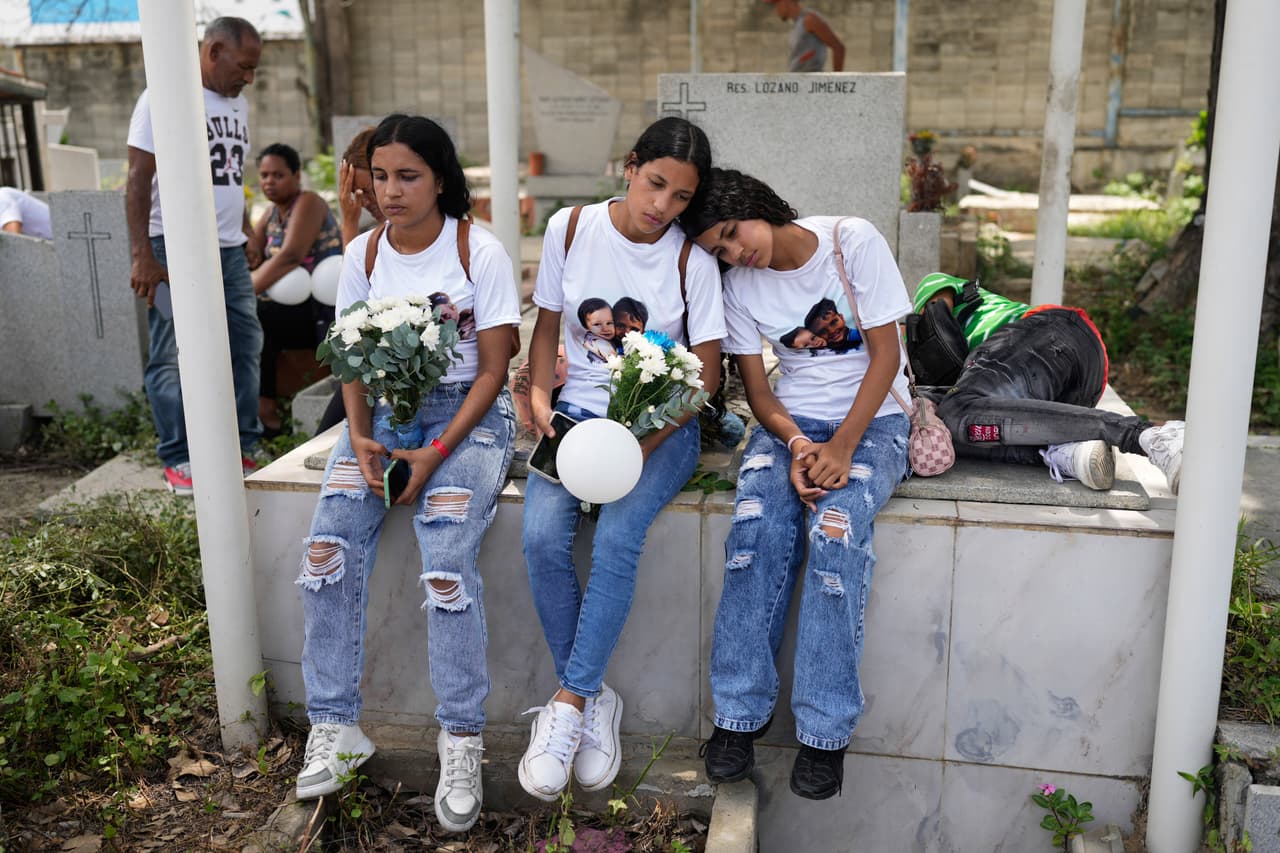 Noemí Marrero, a la izquierda, y sus hermanas se sientan en un cementerio de La Guaira, Venezuela, durante el funeral de los dos hijos de Marrero, quienes fallecieron en los terremotos, el lunes 17 de agosto de 2026.
