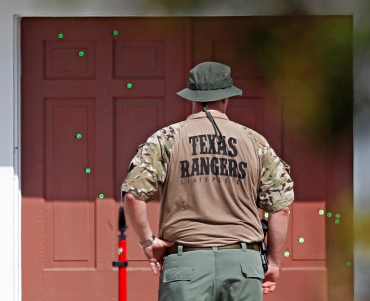 <b>Las marcas de las balas. </b>Un agente observa la puerta tiroteada de la iglesia baptista de Sutherland Springs, Texas, con los balazos marcados en verde.