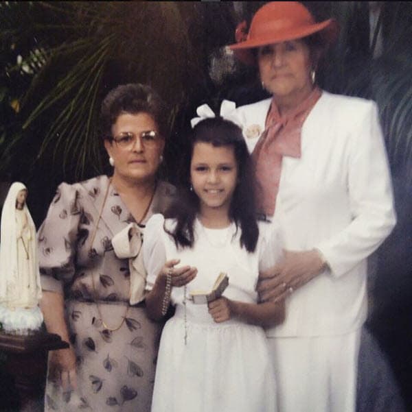 Esta es 
<b><a href="https://www.univision.com/entretenimiento/a-proposito-de-su-ultima-operacion-de-busto-alicia-machado-dice-me-quedaron-de-concurso">Alicia</a></b> en su niñez, al lado de sus dos abuelas cuando hizo su primera comunión.