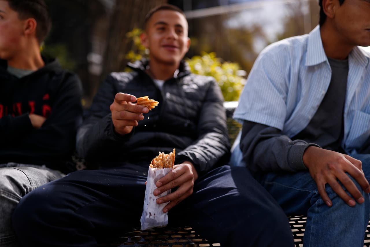 Un hombre come churros de una delgada bolsa de papel comprados de un vendedor ambulante que llevaba su mercancía en una canasta en Ciudad de México el martes 31 de diciembre de 2019. (AP Foto/Rebecca Blackwell)