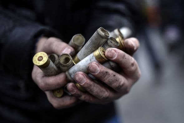 Un hombre muestra los casquillos de balas de grueso calibre disparadas por triopas del gobierno.