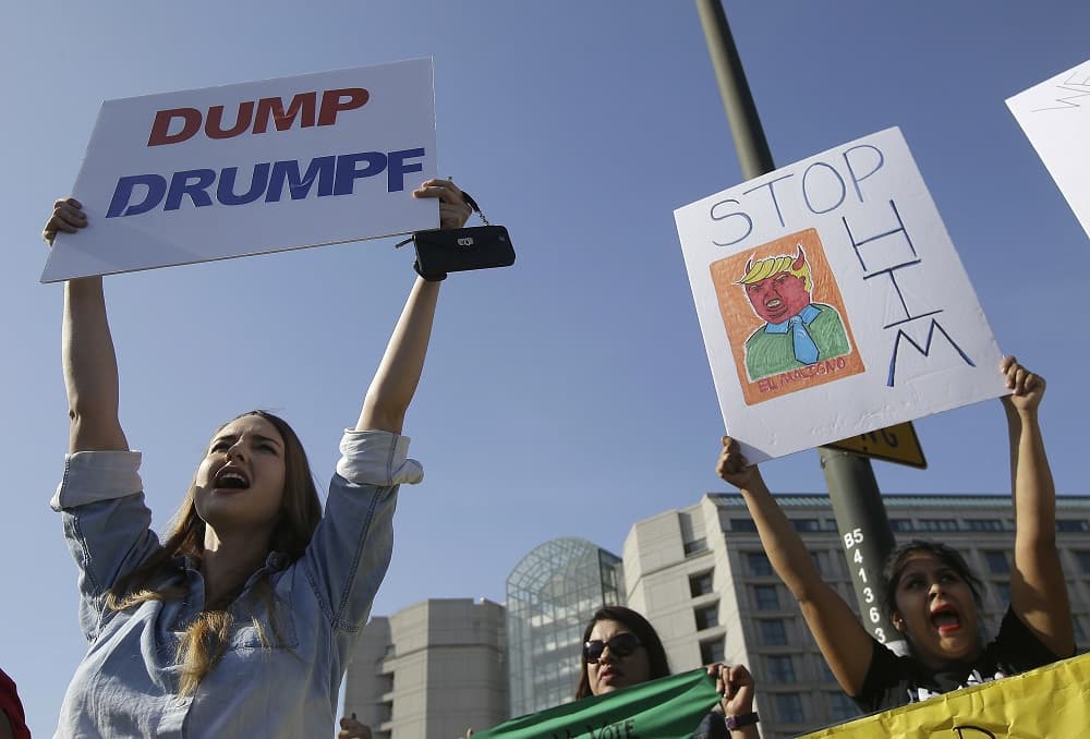 Varias mujeres sostienen carteles contra el candidato Donald Trump frente al hotel Hyatt Regency en Burlingame, California.