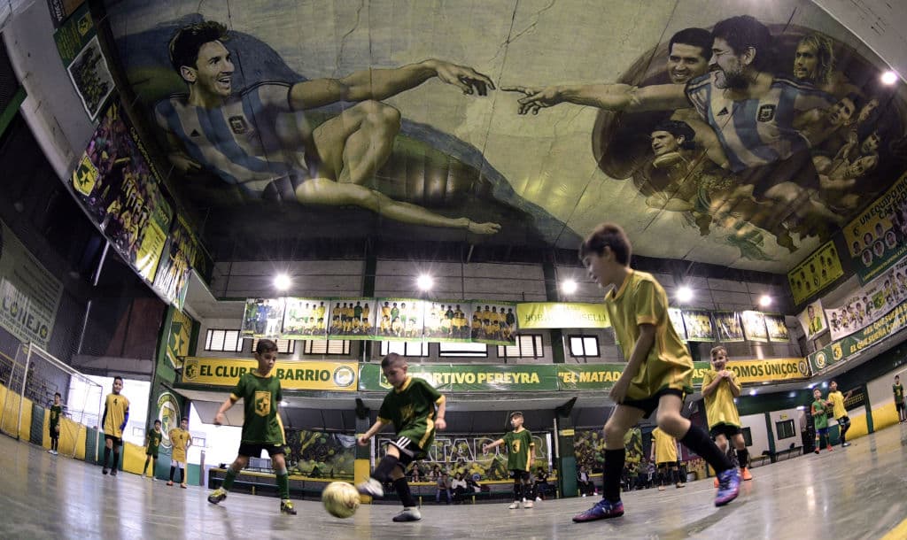 En un deportivo, donde juegan niños, hay un mural inspirado en Maradona y Lionel Messi, también está Juan Román Riquelme en el techo.