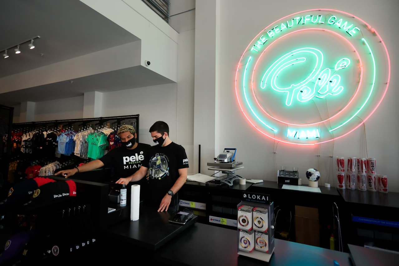 Empleados de un negocio de ropa en Licoln Road conversan con sus mascarillas puestas, frente a la caja registradora. 
<br>