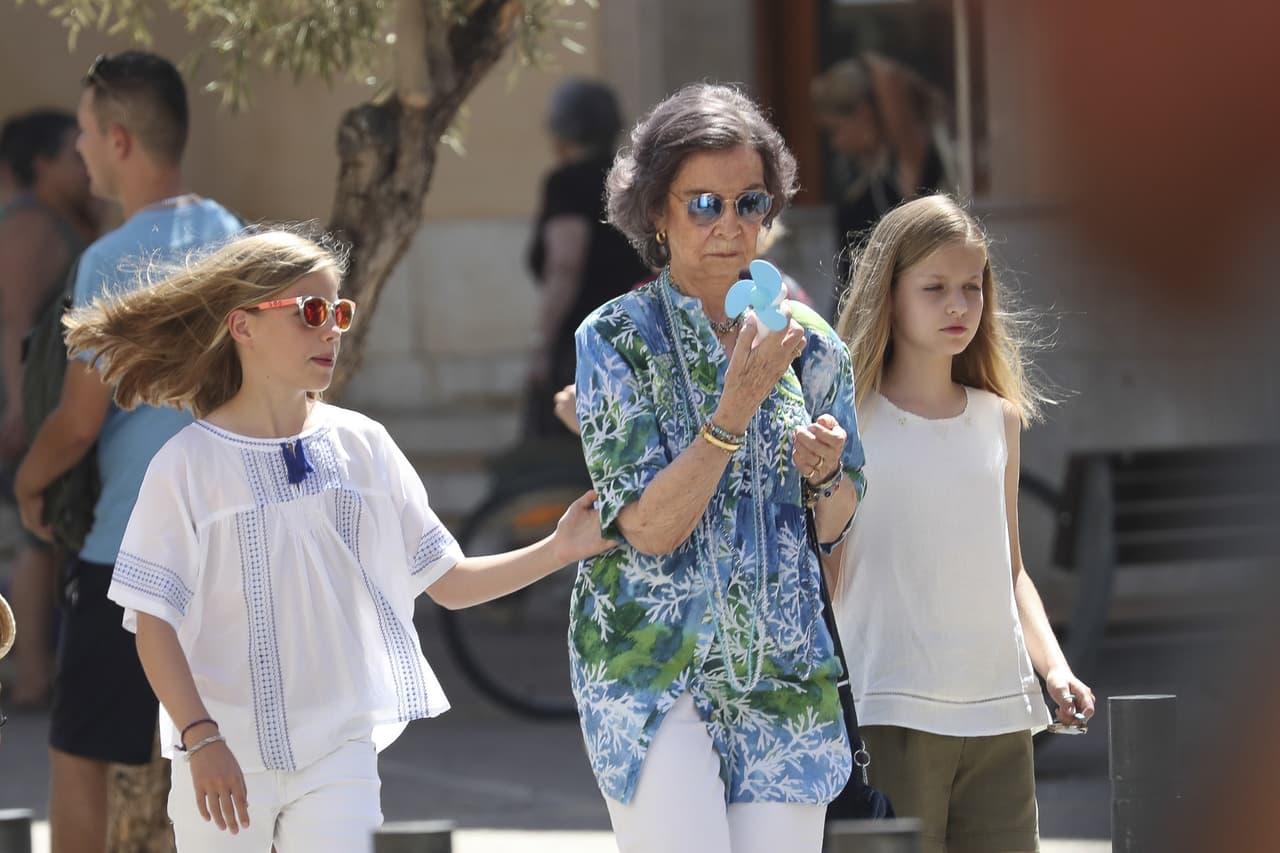 Luciendo gafas de sol cromáticas y abanicándose con un ventilador de pilas, la reina paseó por el centro de Palma, sin separarse ni un minuto de sus dos nietas.