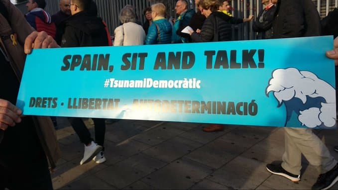 Los grupos de Tsunami Democàtic ya se reunen para protestar camino al Camp Nou. El movimiento independentista cuenta con 100 mil cartulinas con el lema 'Spain, sit and talk', mismas que reparten a la gente para ser mostradas después del himno del Barça.