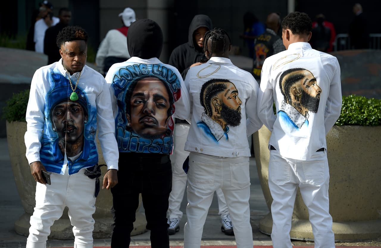 Slum Baby, de izquierda a derecha, Yhung To, Lil Cadi PGE y Lo, del barrio de Crenshaw de Los Ángeles, visten ropas en honor a Nipsey Hussle. (Photo by Chris Pizzello/Invision/AP)
<br>
<br>
<a href="https://www.univision.com/local/los-angeles-kmex/miles-de-fanaticos-dan-el-ultimo-adios-al-rapero-nipsey-hussle">Encuentra toda la información del recorrido del último adiós a Nipsey Hussle aquí. </a>
