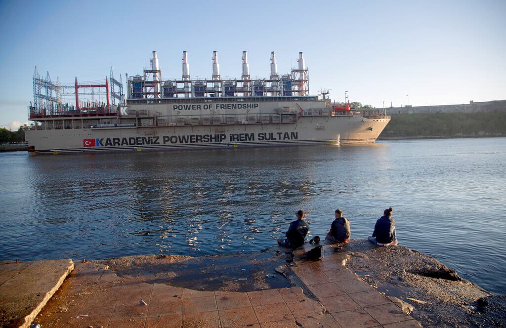 La gente observa la llegada del buque de energía de bandera turca a la Bahía de La Habana en Cuba, el 15 de noviembre de 2022. El barco que transporta una planta eléctrica ha llegado para ayudar a Cuba a satisfacer su demanda de electricidad.