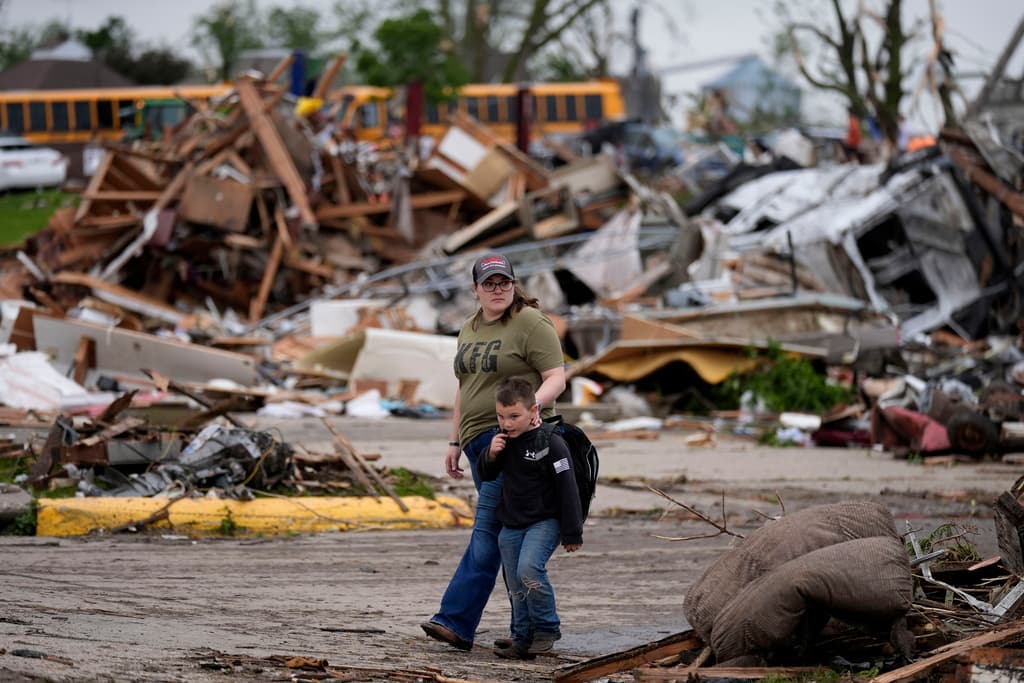 Una mujer y un niño pasan por una zona afectada por el tornado en Freenfield, Iowa, el martes 21 de mayo.