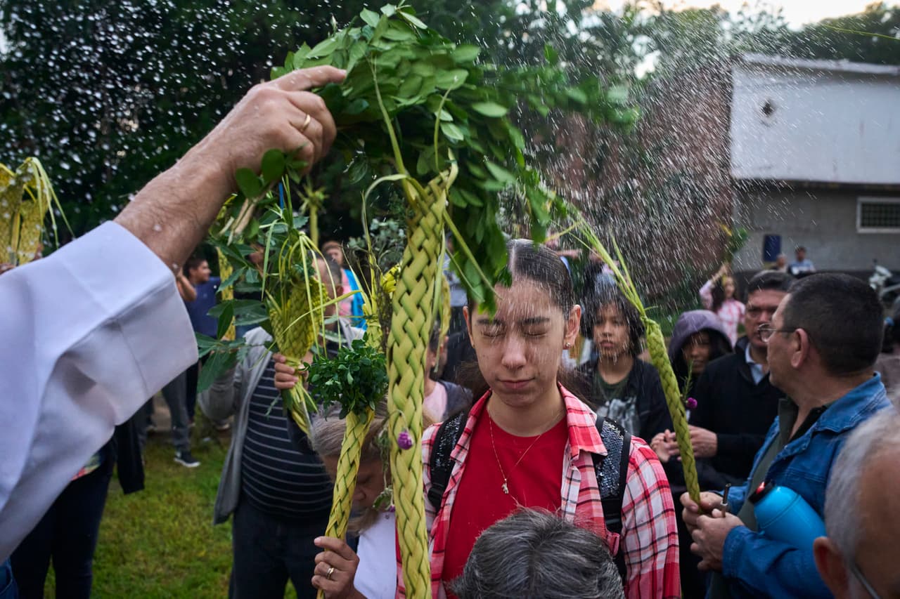 Un sacerdote bendice a los fieles con agua antes de la misa del Domingo de Ramos en el santuario de Luque, Paraguay, el domingo 13 de abril de 2025.