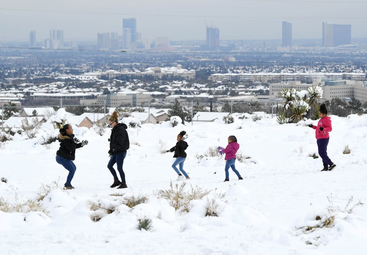 Una familia juega en una zona nevada cerca del centro de Las Vegas, al fondo Las Vegas Strip, la avenida principal de la ciudad. En los últimos días esta ciudad ha experimentado importantes nevadas en su área metropolitana, los primeros eventos de este tipo desde que se inició el registro en 1937.