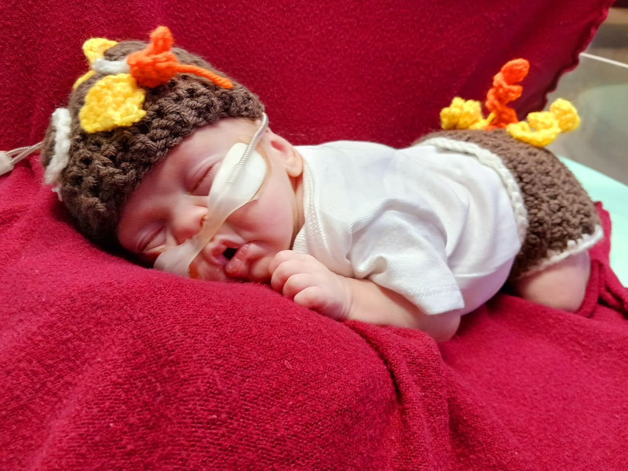 Con su gorro y pañalero tejido de pavo, este bebé toma una tierna siesta.