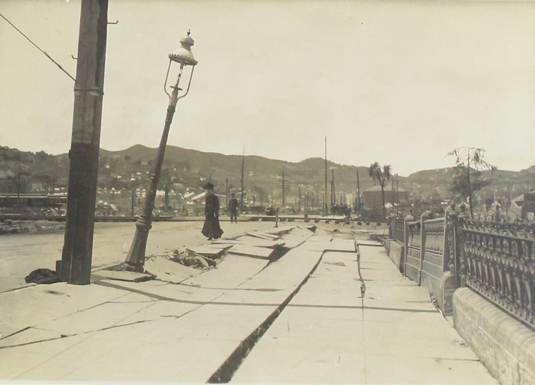 Mujer camina en la calle y observa una banqueta dañada.
