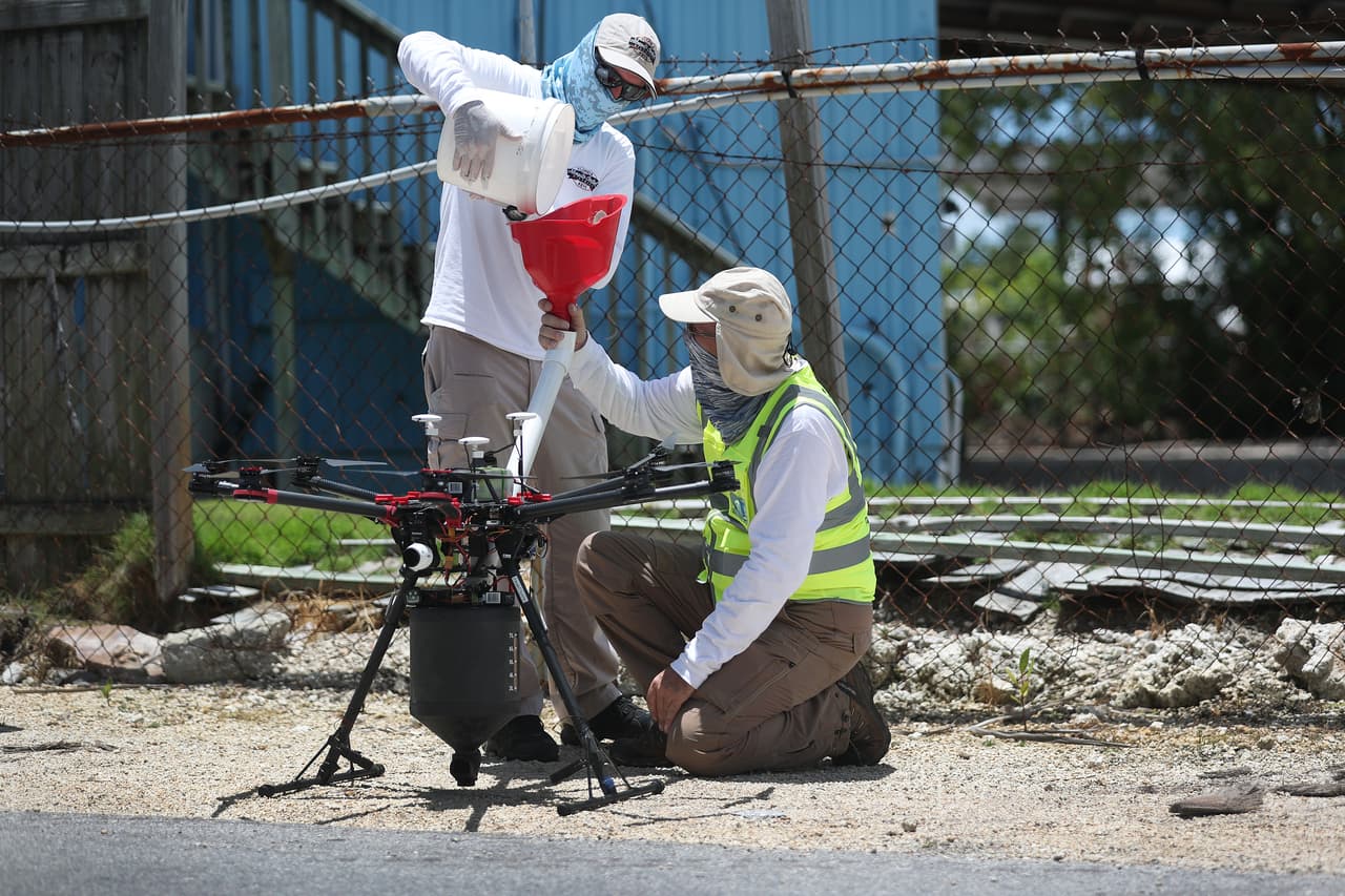 Las autoridades han redoblado sus esfuerzos para erradicar los mosquitos, y en esta imagen se puede observar a los funcionarios del departamento de control de mosquitos cargando un drone con insecticida.