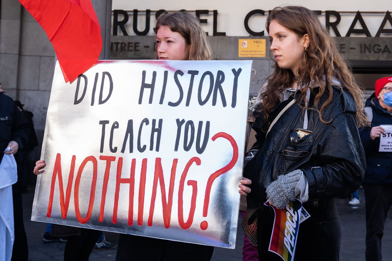 En otras ciudades del planeta, diversas ilustraciones alusivas a Adolf Hitler o con una mano manchada de sangre sobre el rosto,
<b>mientras la gente se preguntaba si la humanidad ha aprendido algo de su trágico pasado.</b> En la imagen, dos manifestantes en Bruselas, Bélgica.