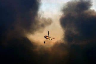 Un helicóptero lanza agua para extinguir uno de los focos del incendio. Otrras seis aerovanes batallan para extinguir el fuego.