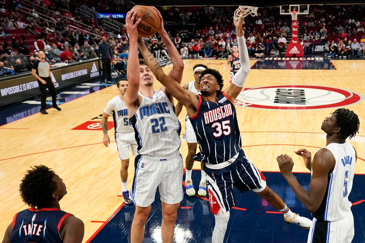 El pívot de los Rockets de Houston Christian Wood y el alero de los Magic de Orlando Franz Wagner compiten por un rebote