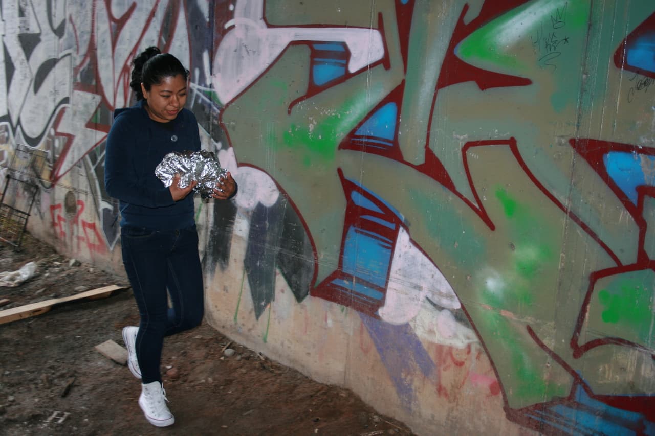 Griselada Martínez lleva pan a jóvenes guatemaltecos, quienes se refugian a un costado de las vías del tren.