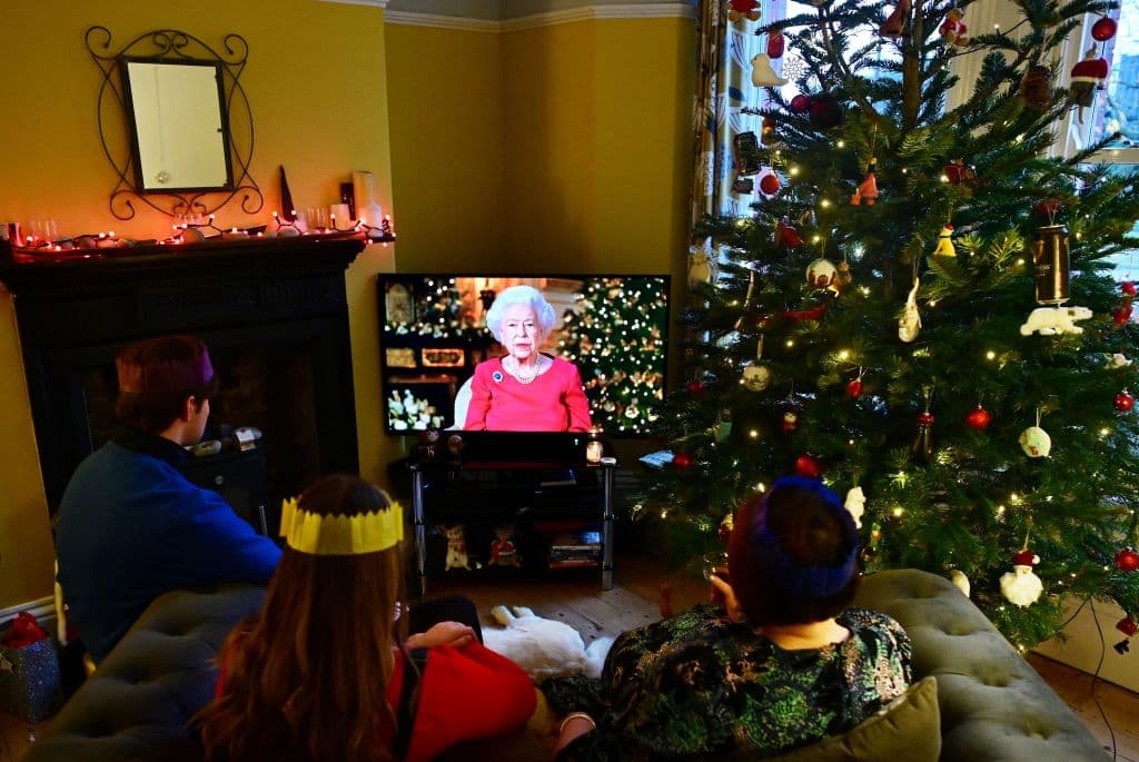 Una familia observa cómo la reina Isabel II de Gran Bretaña transmite su mensaje anual de Navidad, en su casa cerca de Liverpool el 25 de diciembre de 2021.