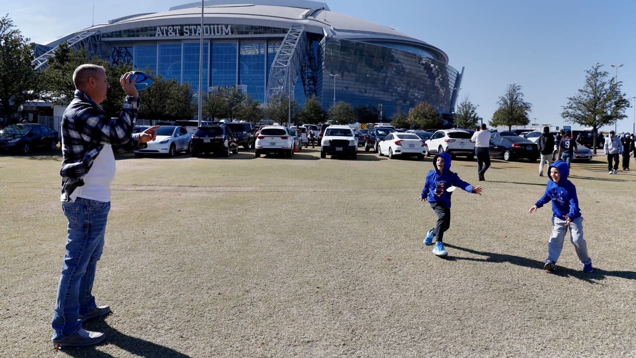 Scott Dial, izquierda, de Topeka Kansas, juega al fútbol con sus hijos, Manning, centro derecha, y Easton, derecha, fuera del estadio ATT antes de un partido de fútbol americano de la NFL entre los Dallas Cowboys y los Raiders de Las Vegas en Arlington, Texas, jueves 25 de noviembre de 2021.