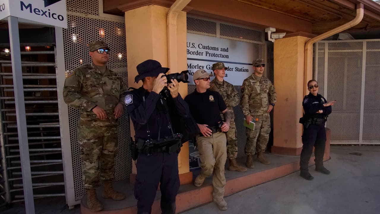 Oficiales de aduanas en el puerto fronterizo Morley, que es utilizado solo por peatones que cruzan entre EU y México, observan los movimientos junto a soldados de la Guardia Nacional.
