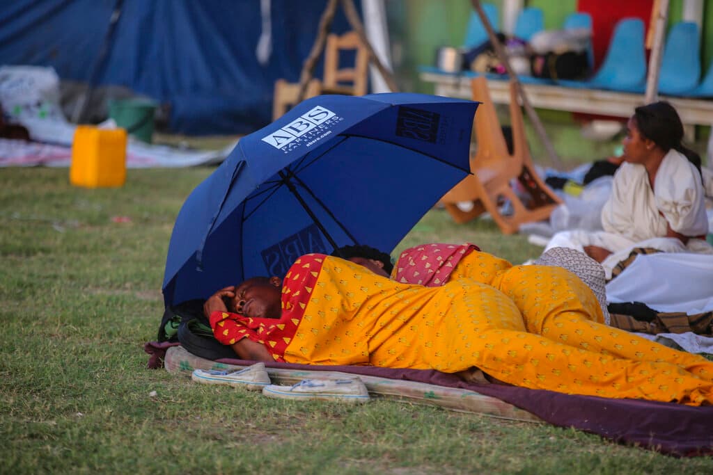 Una pareja duerme en un campo de fútbol en Les Cayes. Estados Unidos y otros países se comprometieron a enviar ayuda al empobrecido país, sumido en la inestabilidad política y social tras el reciente asesinato de su presidente.
<br>
<br>La vecina República Dominicana anunció, asimismo, el envío de 10,000 raciones de alimentos y equipo médico. Cuba y Ecuador también desplegarán equipos de ayuda; mientras que México, Chile, Argentina, Perú and Venezuela ofrecieron apoyo.