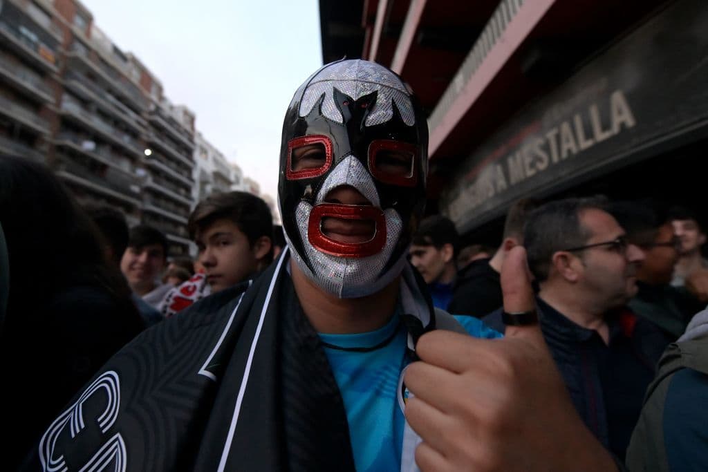 Un aficionado posa con una máscara de luchador en las afueras de Mestalla, mientras alienta a su equipo.