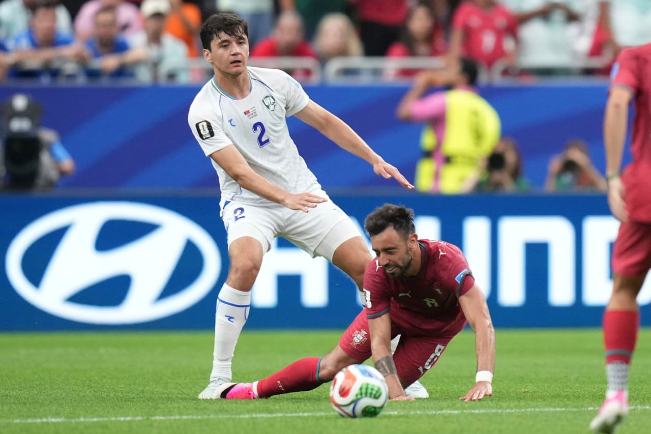 Abdukodir Khusanov (2) de Uzbekistán detiene a Bruno Fernandes (8) de Portugal durante el partido de fútbol del Grupo K de la Copa Mundial entre Portugal y Uzbekistán