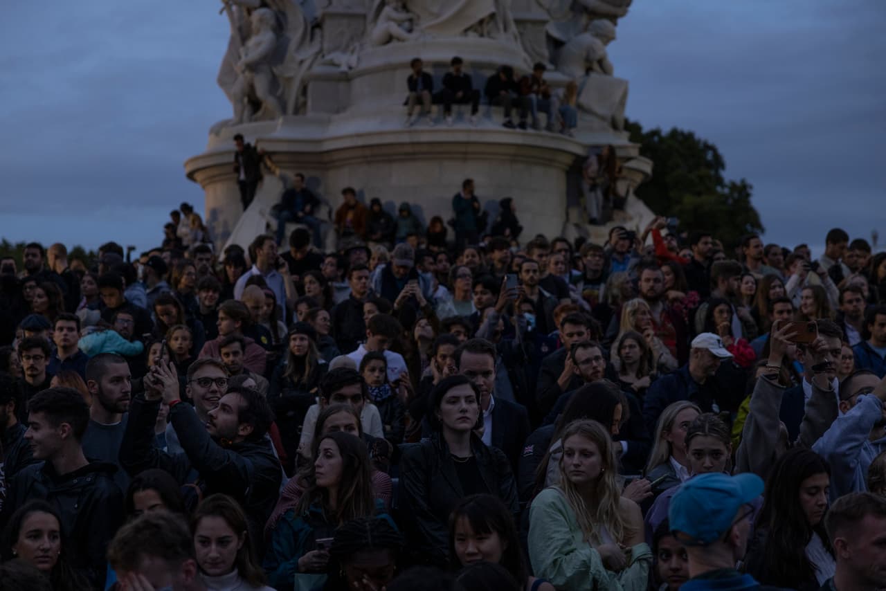 La multitud concentrada en el monumento de la reina Victoria, frente al palacio de Buckingham. Tras el anuncio de la muerte de la reina Isabel II, locales y turistas han llegado a rendir tributo con flores, cartas y peluches, pero también a tomar fotografías para registrar cómo se vive en Londres ese momento.