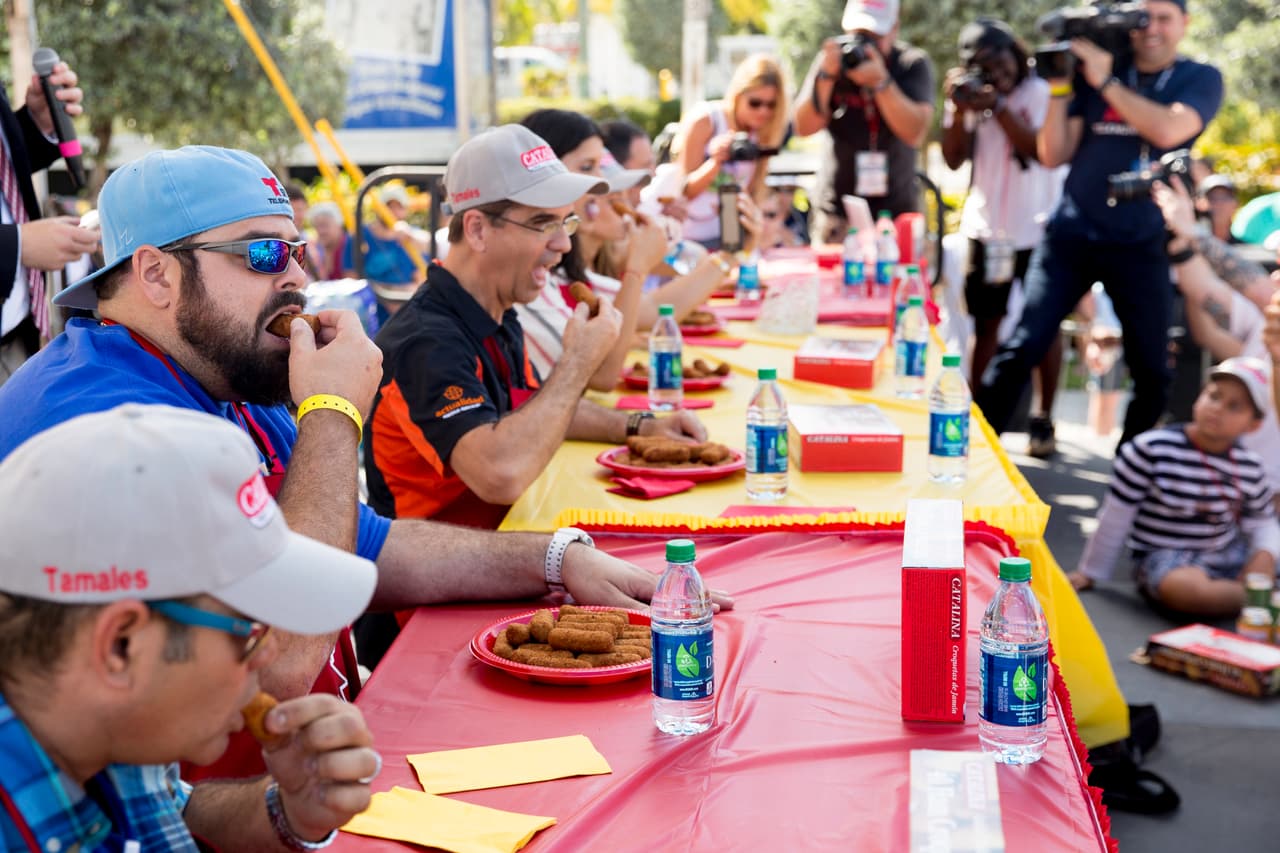 Asistentes al carnaval compiten para saber quién es capaz de comer más de las tradicionales croquetas cubanas la Calle Ocho.