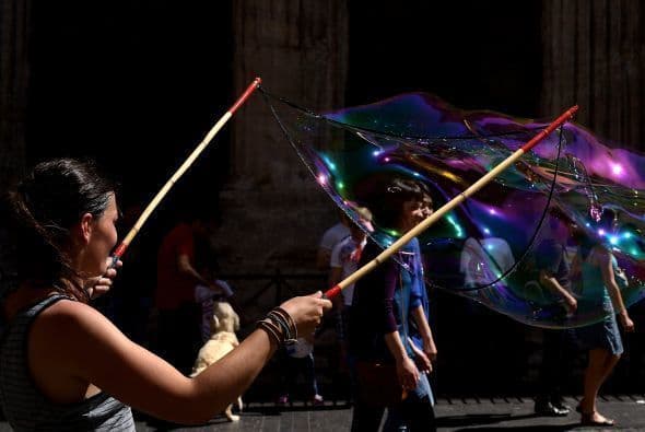 Un artista de la calle hace una burbuja de jabón gigantes en el centro de Roma.