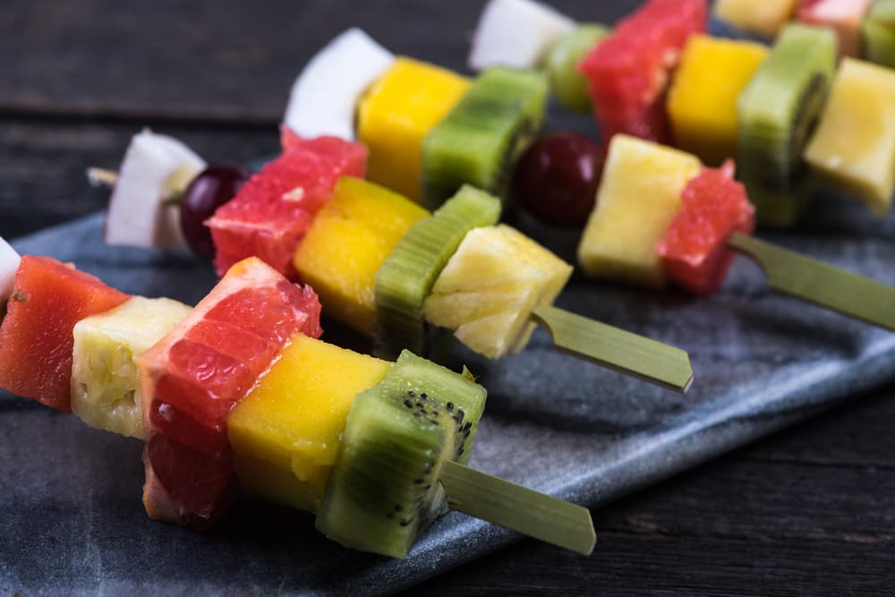 Estas brochetas llevan plátanos, manzanas rojas, piña y puedes agregar otras frutas que sean tus favoritas.