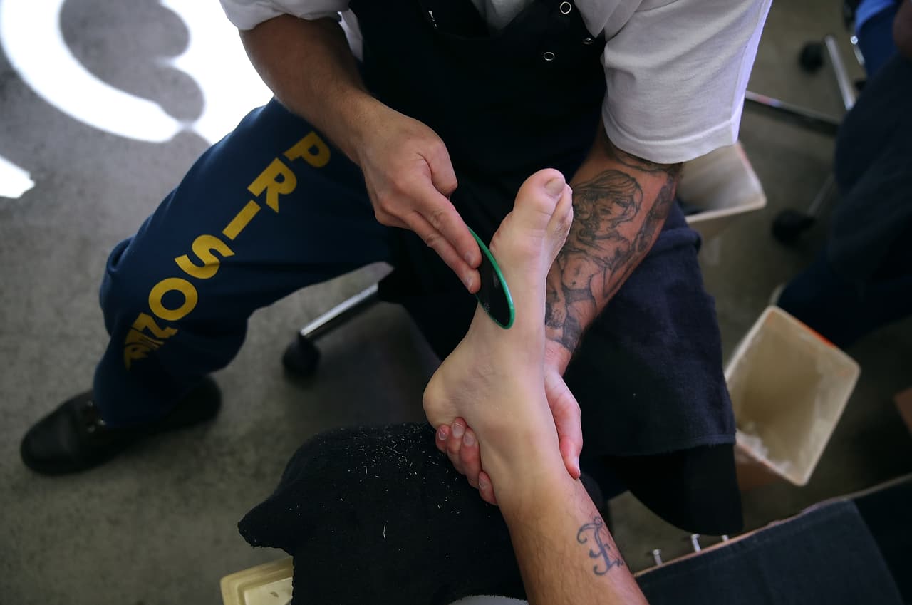 Un preso le hace un pedicure a otro durante esta clase.