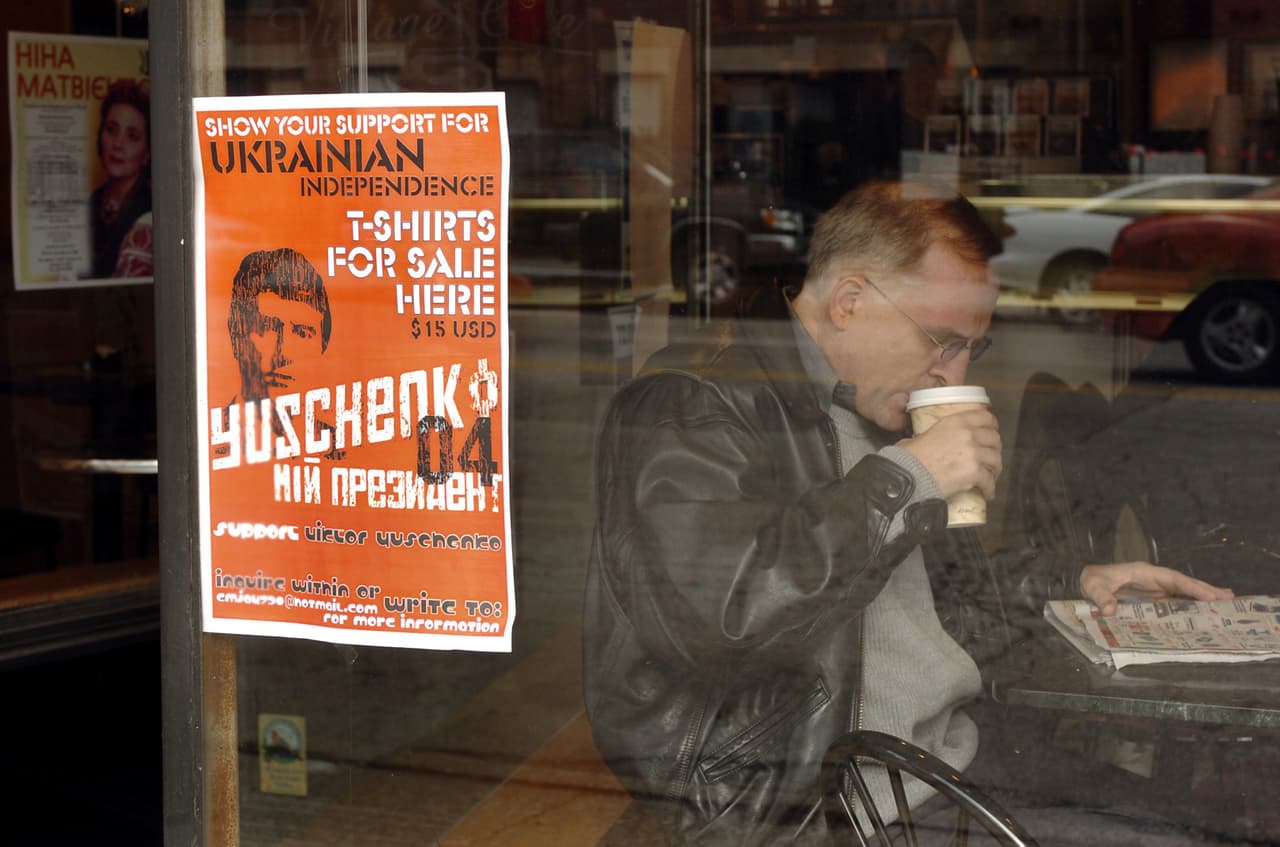 Un hombre disfruta de un café en una cafetería en el vecindario Ukrainian Village de Chicago. En la ventana se encuentra un cartel que anuncia la venta de camisetas en apoyo del líder de la oposición, en Ucrania, Viktor Yushchenko.