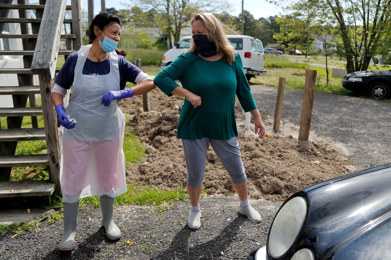 Dos vecinas se saludan respetando las nuevas normas en Maryland.