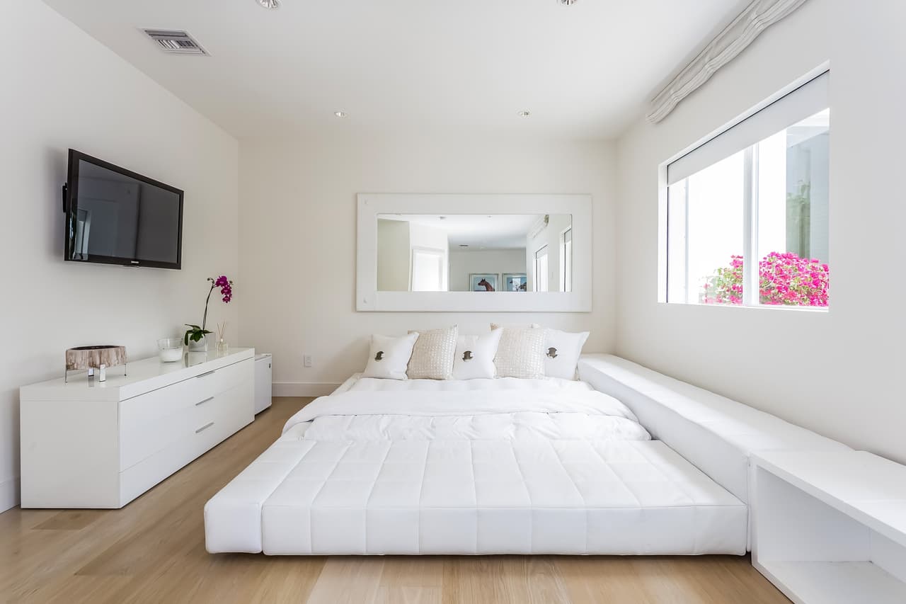 Esta otra habitación tiene vista al patio. Los únicos elementos que sobresalen son el televisor negro en la pared y el color magenta de la planta que se asoma por la ventana.