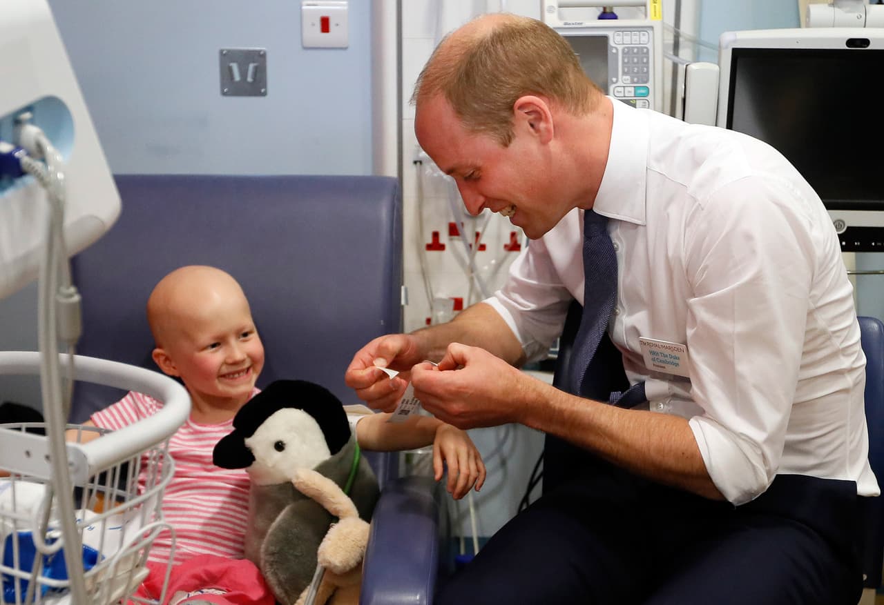 LONDON, UNITED KINGDOM - MAY 16: Prince William, Duke of Cambridge, right, attaches a name tag to patient Daisy Wood, 6, during a visit to the Royal Marsden hospital on May 16, 2017 in Sutton, England. The Duke of Cambridge, President of the Royal Marsden NHS Foundation Trust, visited the hospital's facilities in Sutton. During the visit, which marks 10 years since His Royal Highness became President of the centre, The Duke accompanied staff as they went about their daily activities in treating and caring for patients. (Photo by Kirsty Wigglesworth - WPA Pool/Getty Images)