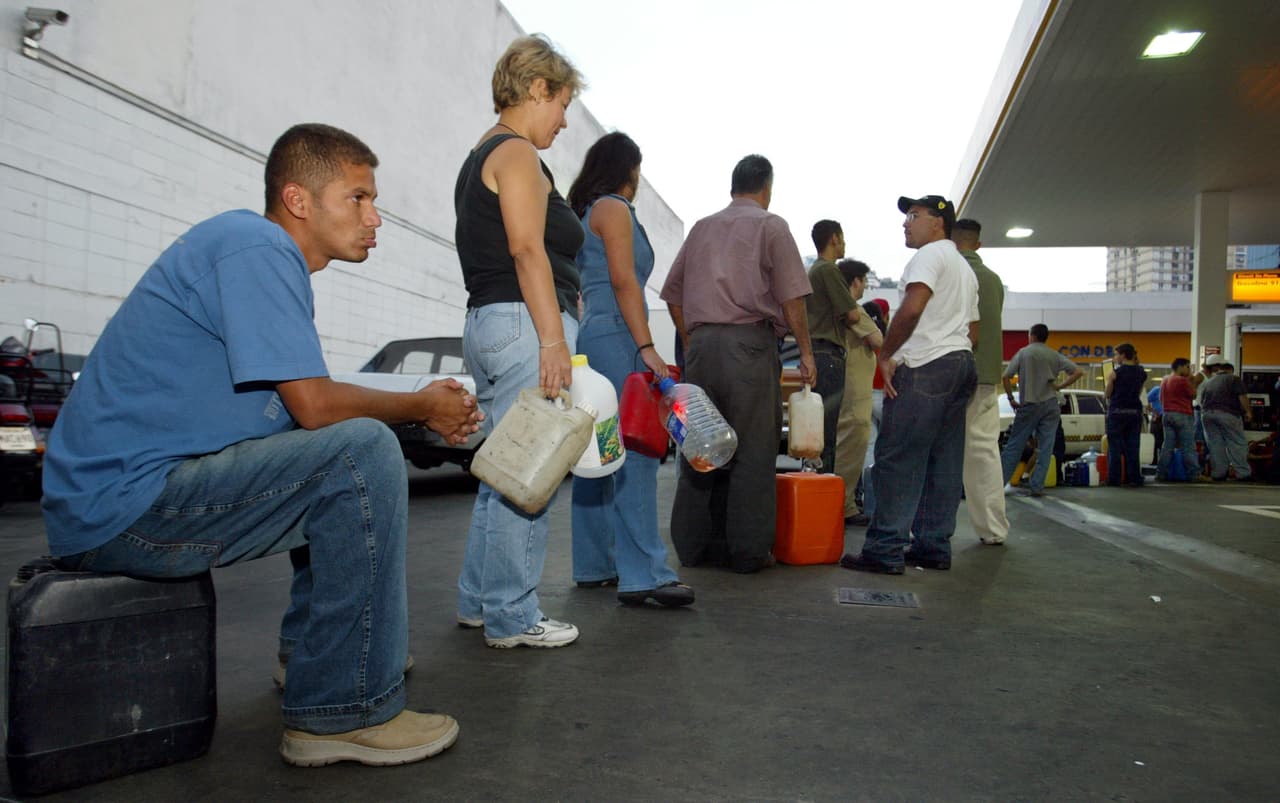 <b>Paro petrolero.</b> Las protestas contra el gobierno de Hugo Chávez no terminaron con el golpe de Estado fallido. Los partidos de oposición, gerentes de la petrolera estatal, la iglesia católica, los medios de comunicación y manifestantes en las calles exigían la renuncia del Presidente. En diciembre de 2002 se estableció una mesa de diálogo para intentar conciliar a la oposición con el chavismo. Sin embargo, días después se convocó una huelga de la industria petrolera que inicialmente duraría 24 horas. El cese de actividades, que exigía la renuncia del presidente o la convocatoria a un referéndum revocatorio se convirtió en una huelga indefinida que dejó a Venezuela sin gasolina, pese a ser uno de los grandes productores de petróleo del mundo. En la fotografía, venezolanos hacen fila para comprar combustible en Caracas en plena crisis de desabastecimiento, el 19 de diciembre de 2002.