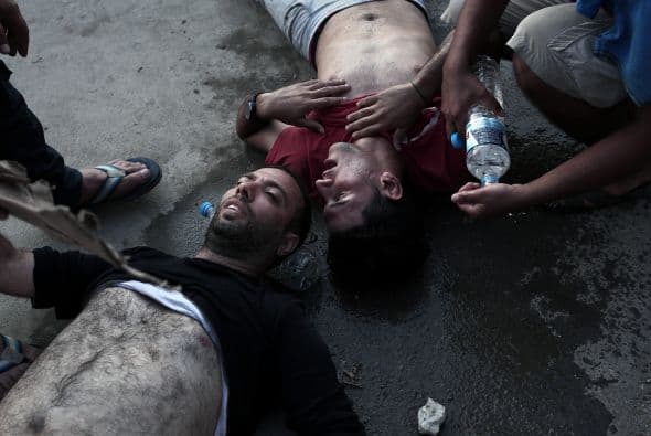 Hombres colapsando antes de ser registrados por la policía en la isla griega de Lesbos.