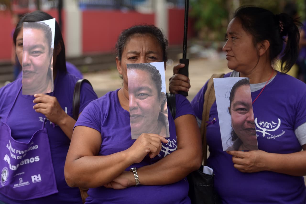 Mujeres llevan imágenes con parte del rostro de la líder comunitaria Aida Maria Paniagua, una defensora de los derechos de las mujeres que fue asesinada el 4 de marzo por miembros de la "Mara 18", según la policía.