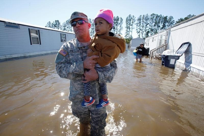 El sargento de la Guardia Nacional Jeremy Stellhorn carga a la niña de 2 años Cathalawa Olivia desde su casa en un parque de residencias móviles en Lumberton. (REUTERS/Jonathan Drake)