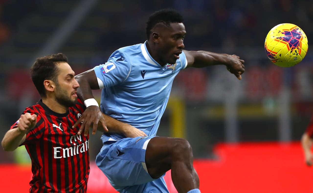 Bastos del SS Lazio salta por el esférico junto con Hakan Calhanoglu del AC Milan.