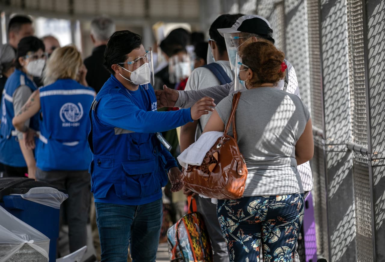 <b>¡Felicidades!</b> Un miembro del personal de la Organización Internacional de las Naciones Unidas para las Migraciones felicita a los inmigrantes en la frontera entre Estados Unidos y México, ya que a un grupo de al menos 25 solicitantes de asilo se les permitió viajar desde un campamento de migrantes en México a los Estados Unidos el 25 de febrero de 2021 en Matamoros, México.