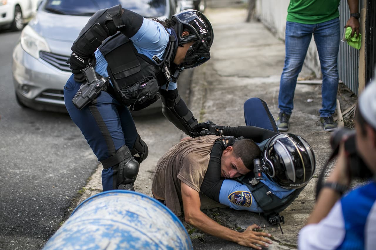 La policía forcejea con uno de los 6 arrestados durante la refriega.
<br>