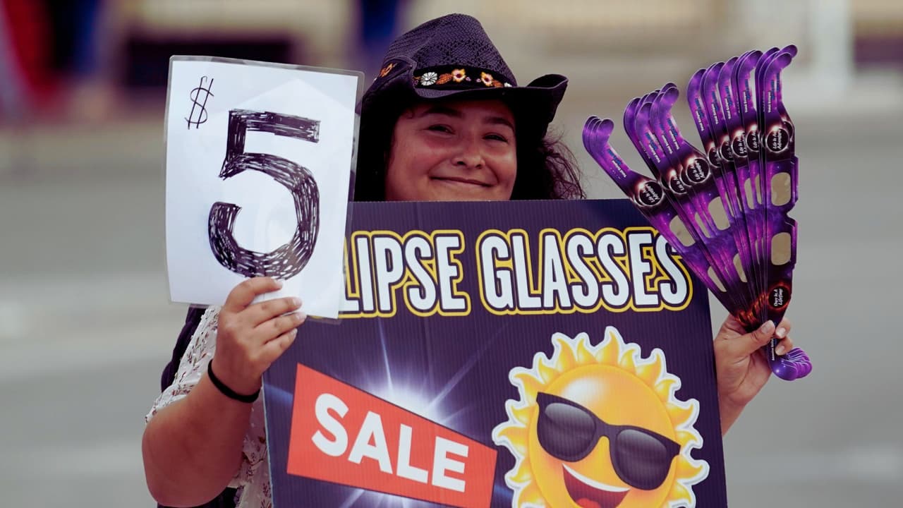 Una mujer vende gafas especiales para ver el eclipse solar anular, o anillo de fuego, el sábado 14 de octubre de 2023, en San Antonio, Texas.