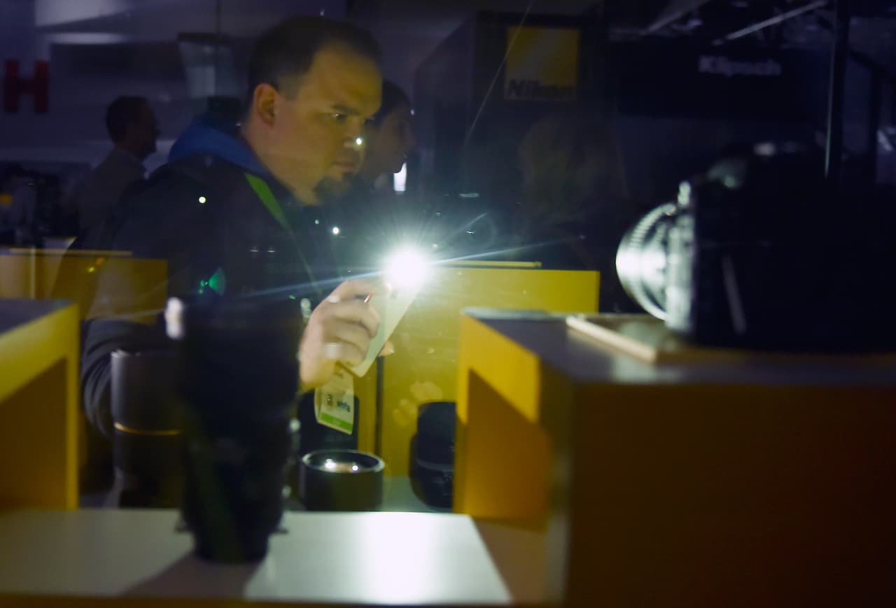 Un hombre usa la luz de su propio teléfono para poder ver algunos artículos expuestos en la feria.