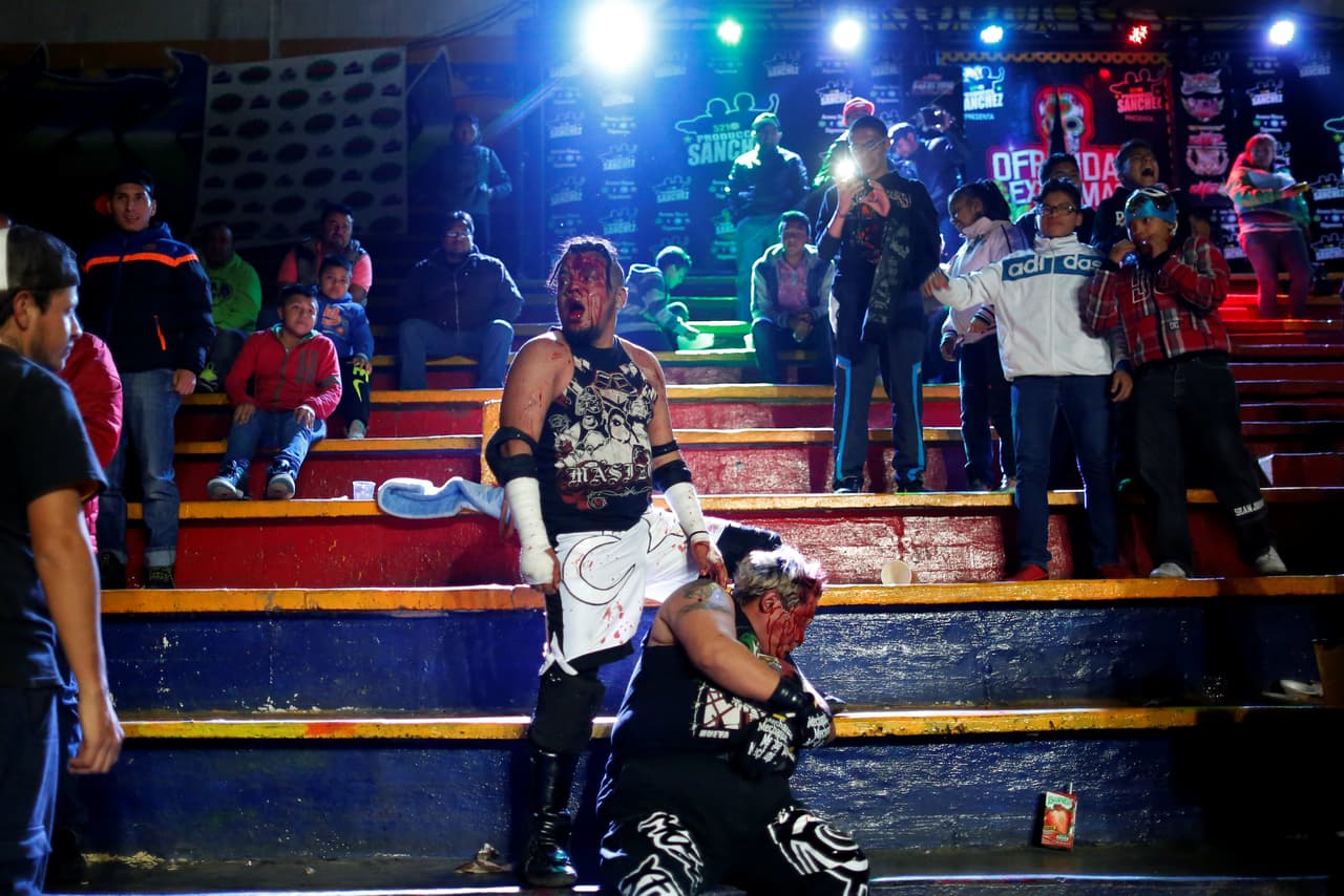 Los luchadores conocidos como Cíclope y Mosco X-Fly se enfrentan en una pelea fuera del ring y en medio de los espectadores. (Foto e información de Carlos Jasso/Reuters)