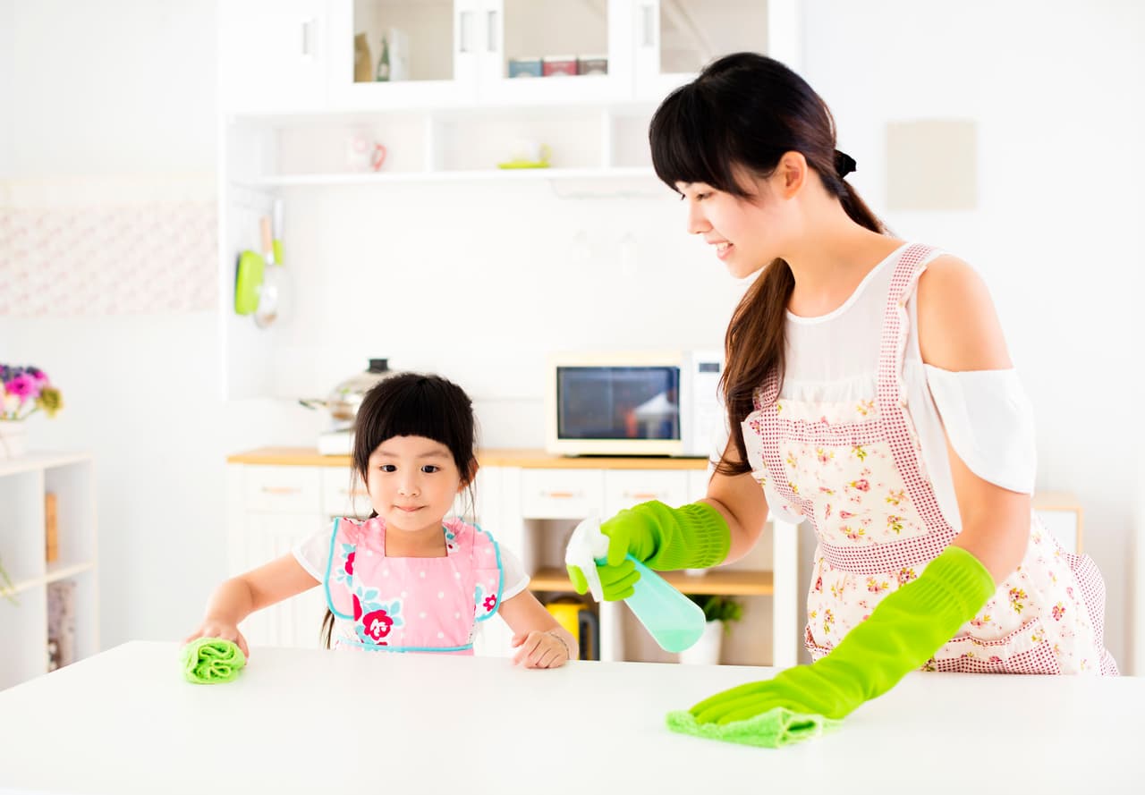 little girl helping her mother clean table in the kitchen