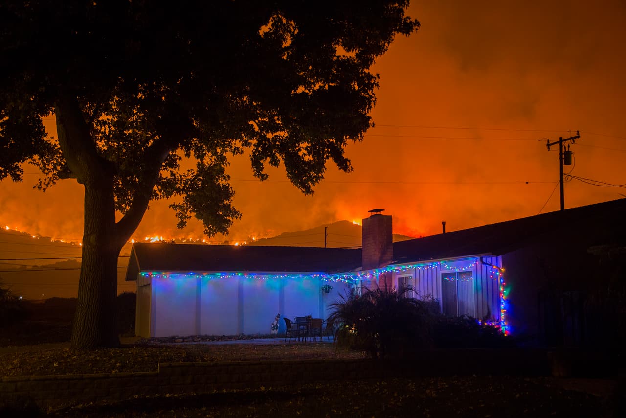 Las luces navideñas que decoran las casas en el condado de Santa Barbara se ven opacadas por las llamas que acechan ahora a este vecindario en Carpinteria, a donde se expandió el domingo el fuego Thomas, que ya ha consumido más de 230,500 acres de terreno desde su inicio en el condado de Ventura.